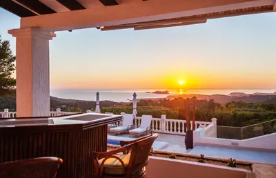 Außenbereich mit Bar auf der Terrasse und Sonnenuntergang im Meer